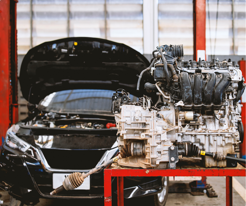 Engine removed from a black car in a repair shop, sitting on a red cart. | Lambert's Auto Repair