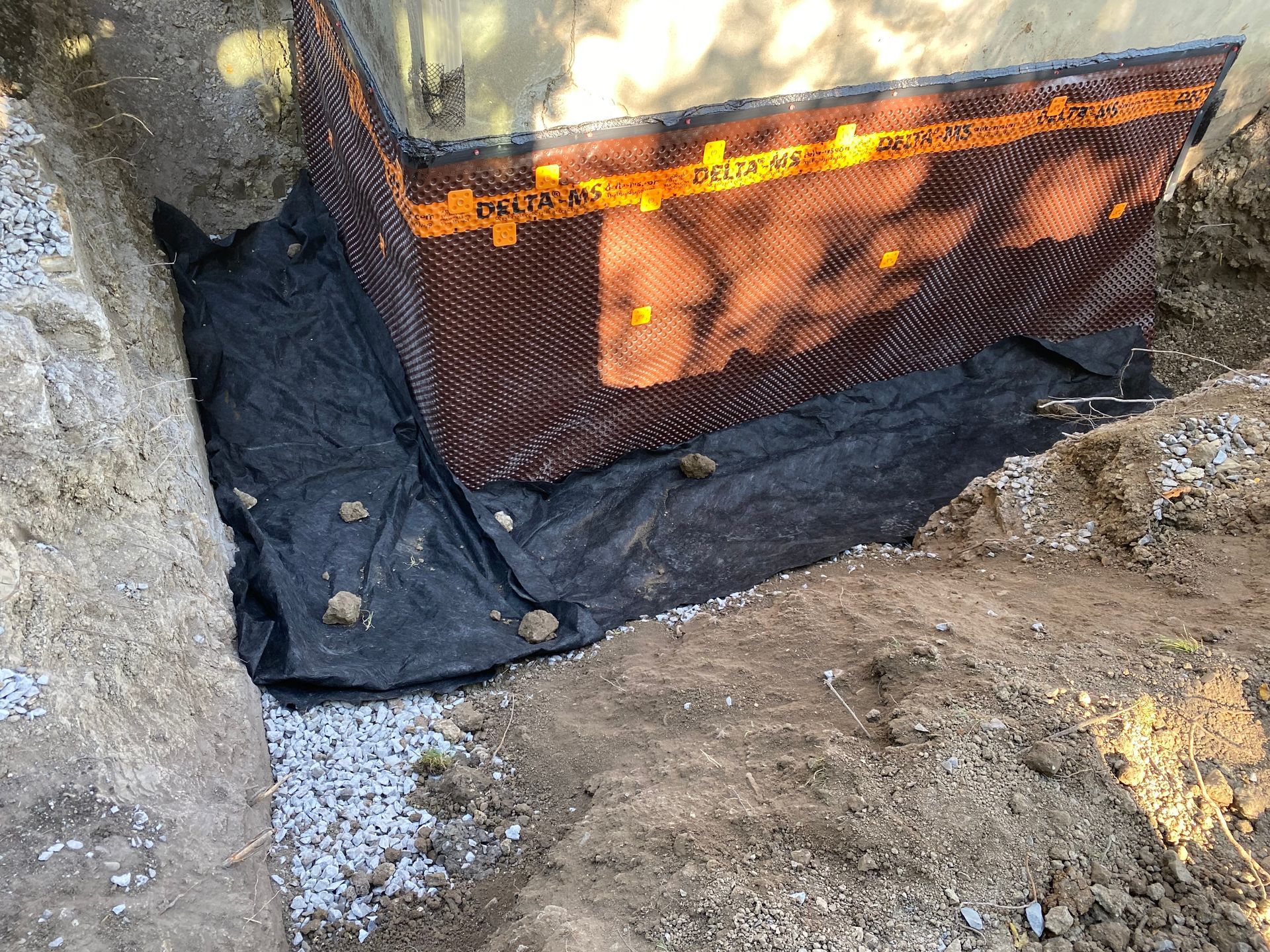 Un système de drainage est en cours d'installation sur le côté d'un bâtiment.