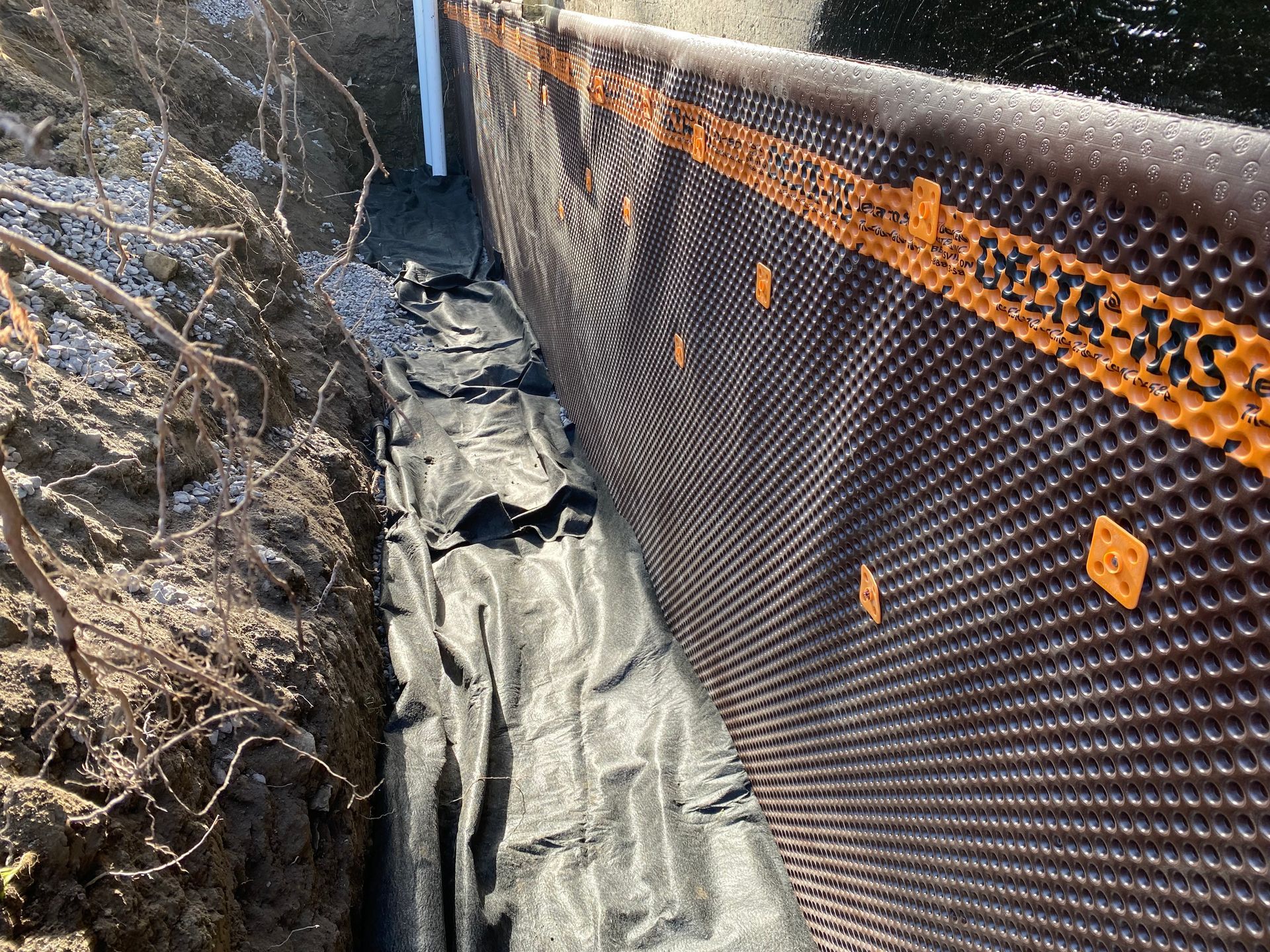 Un système de drainage est en cours d'installation sur le côté d'un bâtiment.