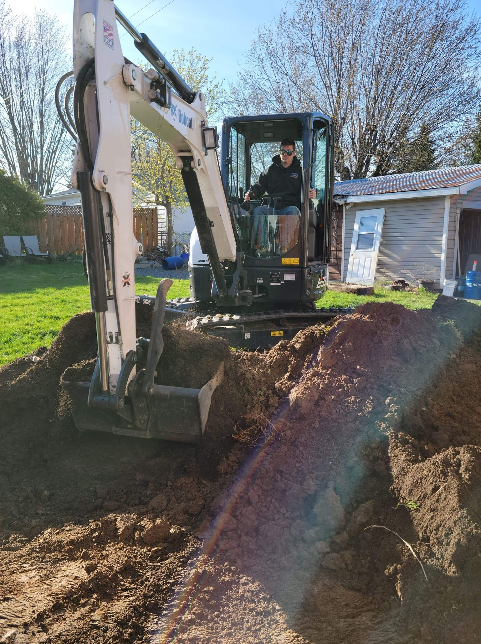 Un homme conduit une excavatrice dans un trou dans le sol.