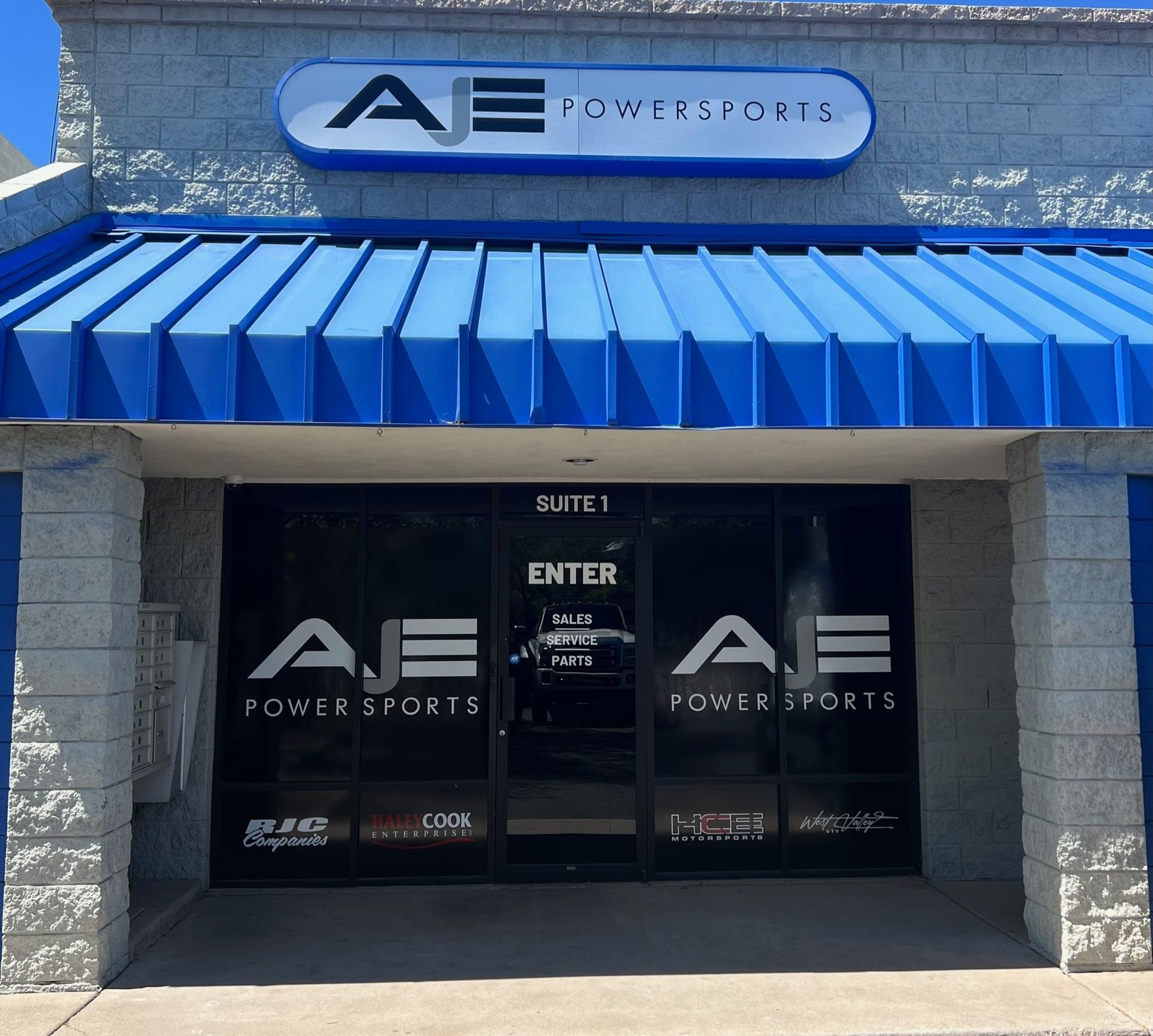 A building with a blue awning that says AJE Powersports