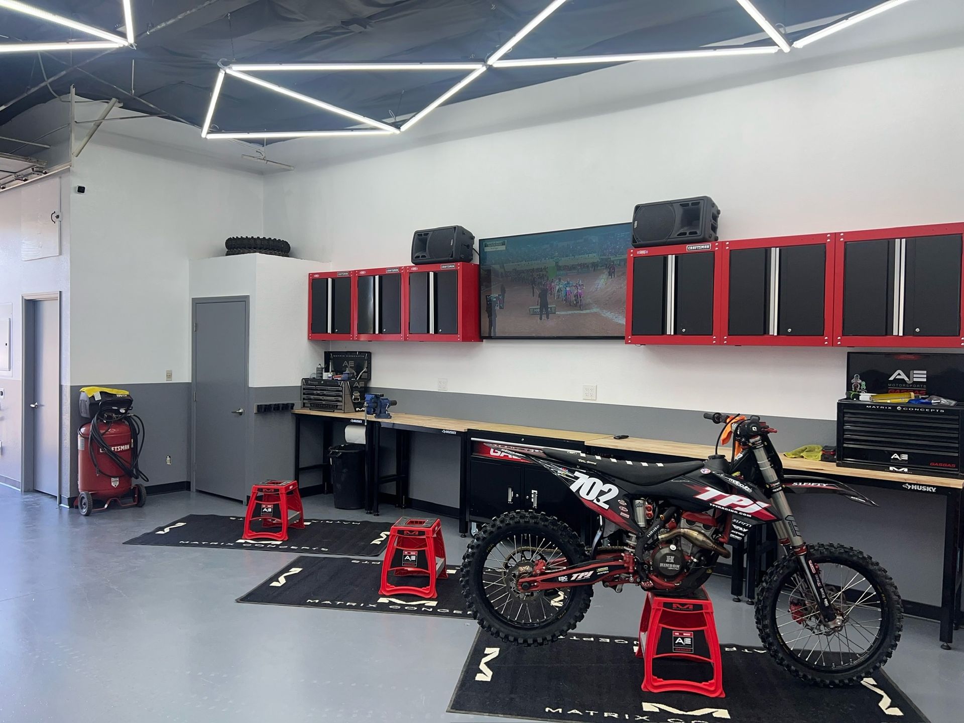 A dirt bike is parked in a garage with red stools