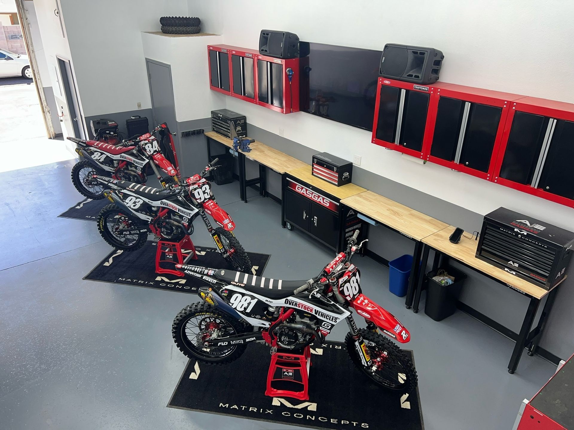 A row of dirt bikes are parked in a garage.