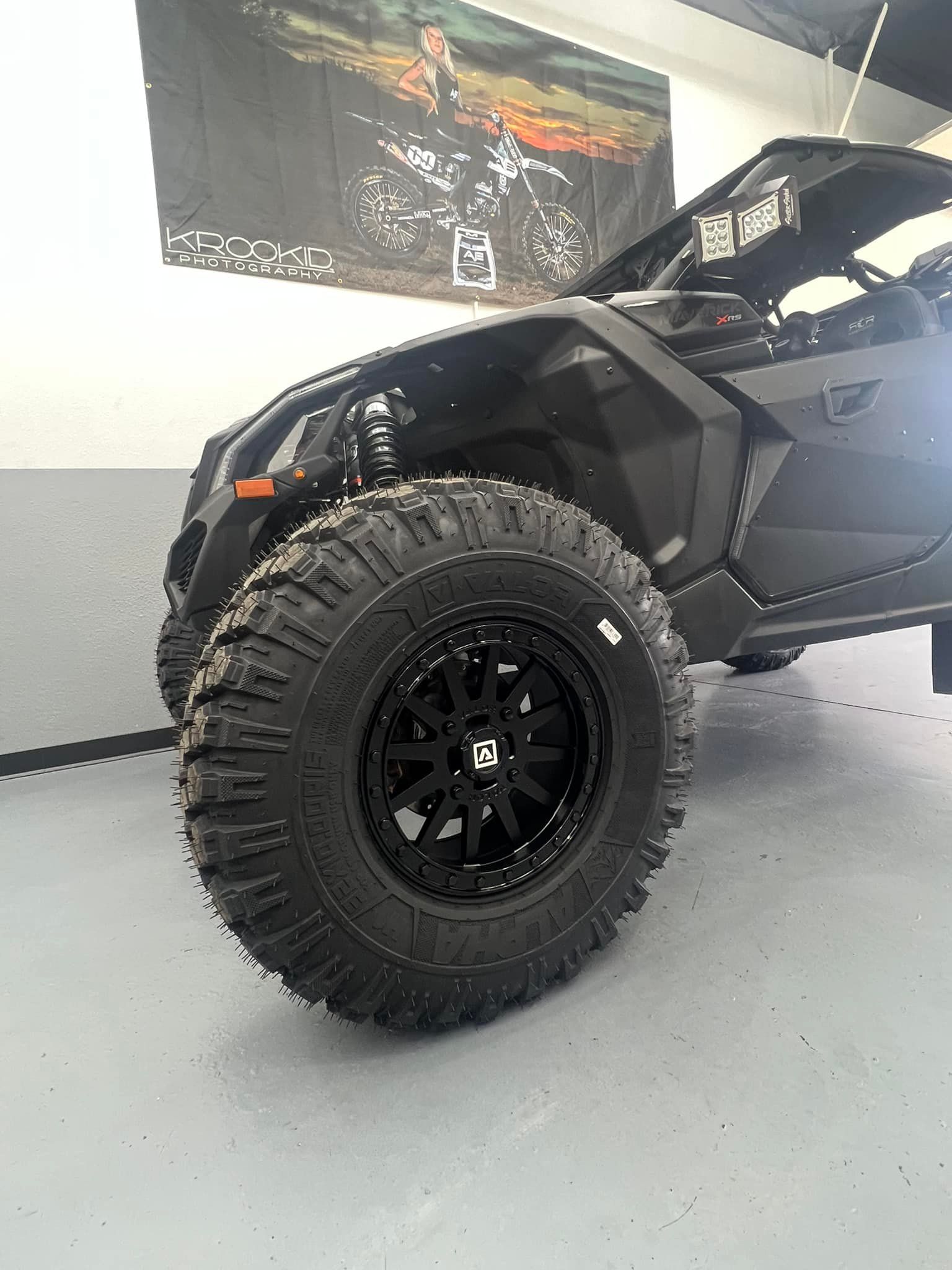 A black atv with black wheels and tires is parked in a garage.