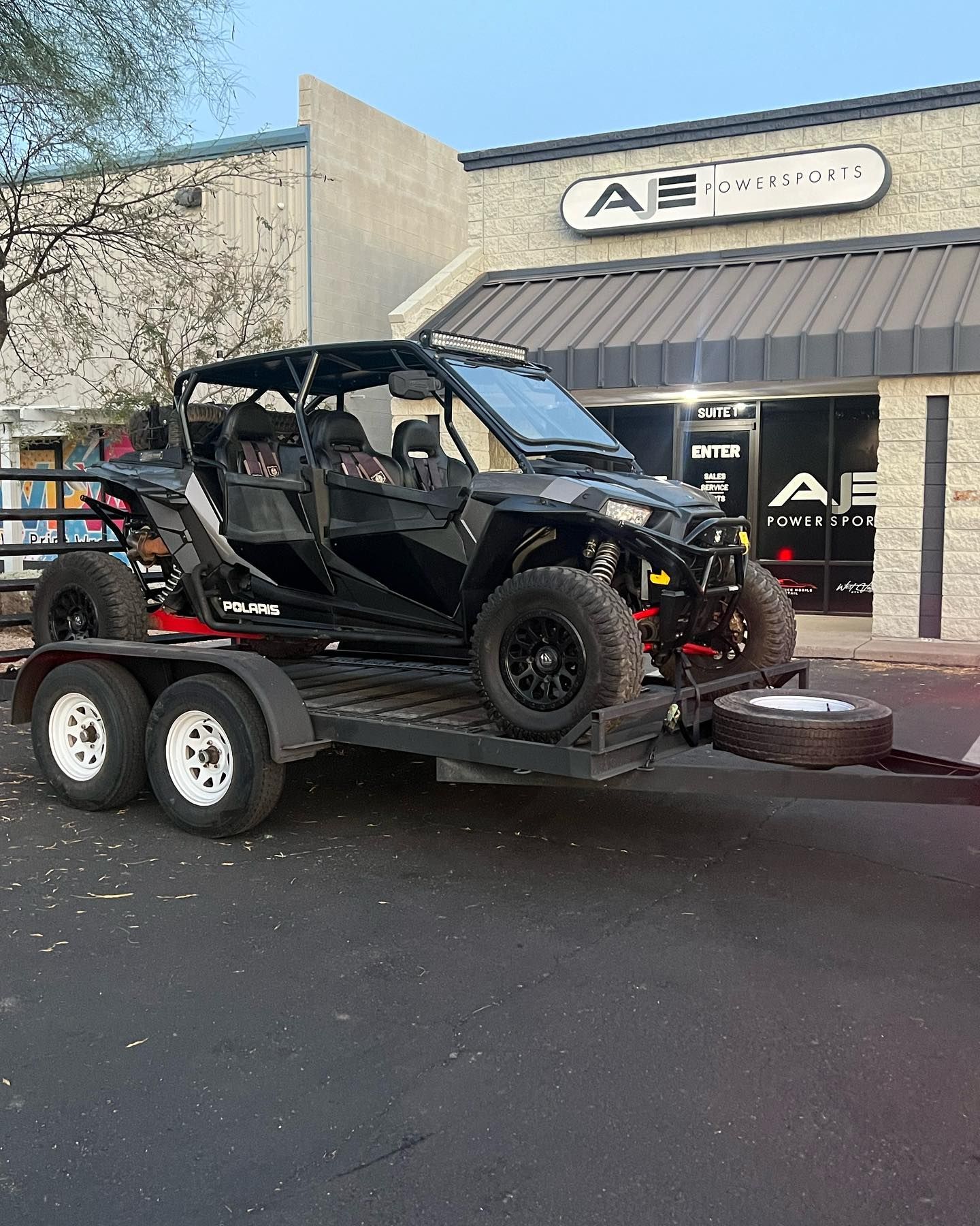 A black atv is being towed on a trailer.
