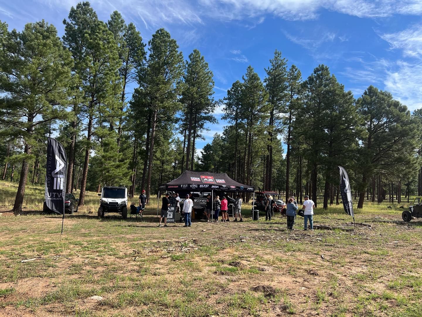 A group of people are standing in a field with trees in the background.