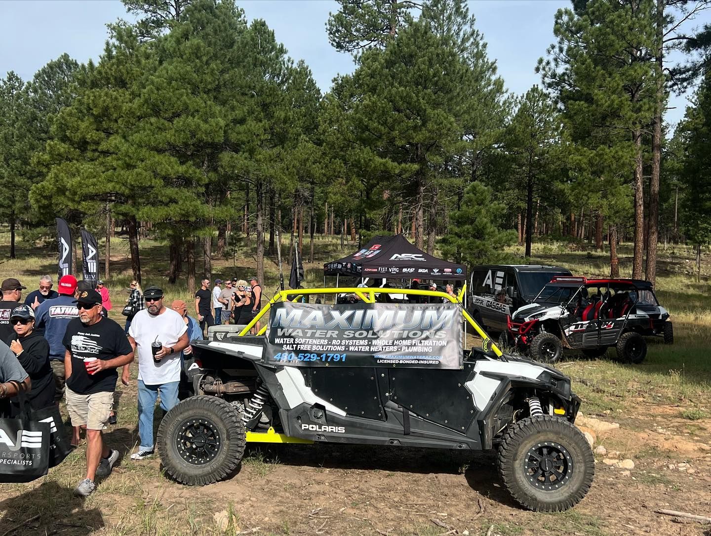 A group of people are standing around a atv in a field.
