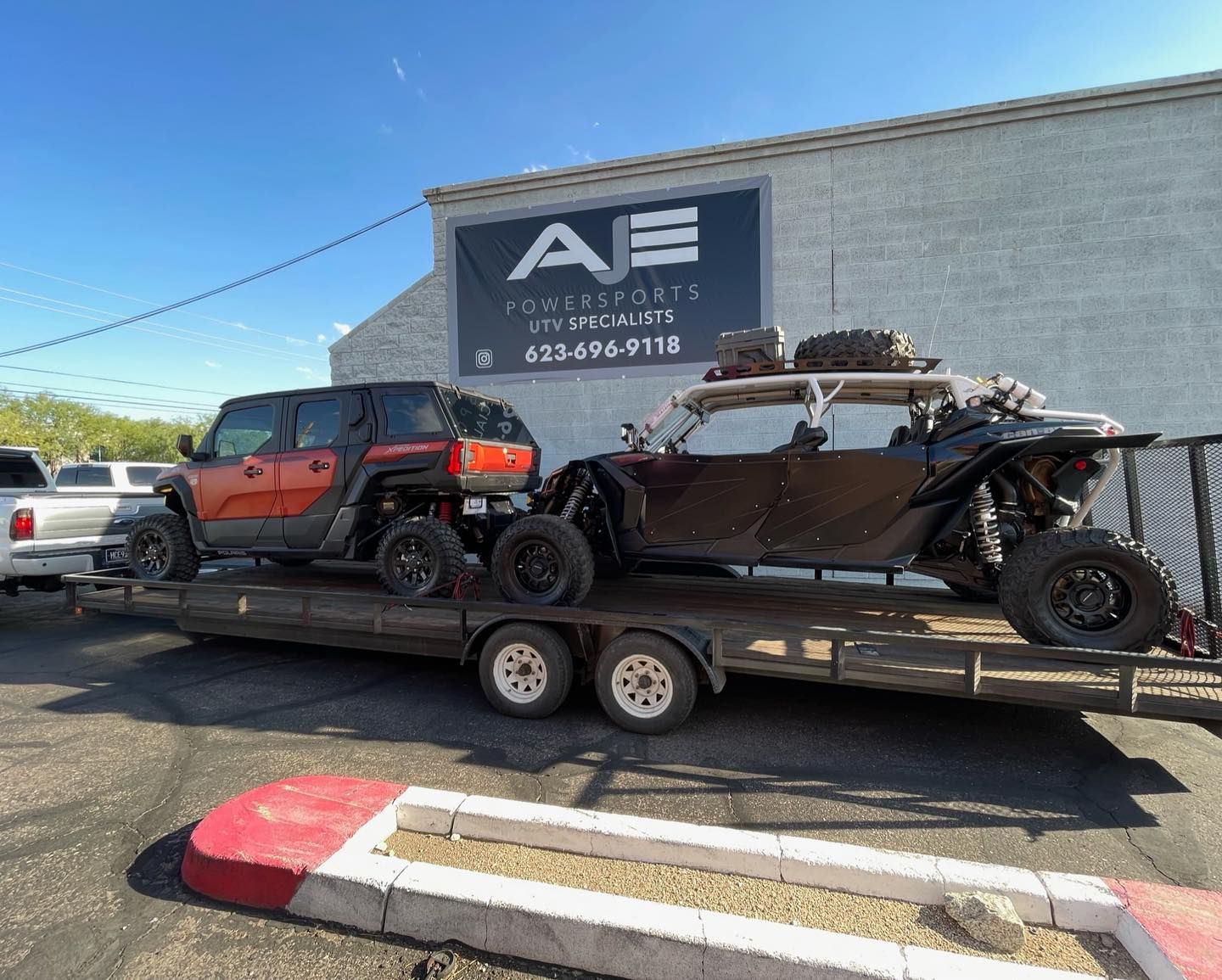 A truck and a canoe are on a trailer in front of a building.