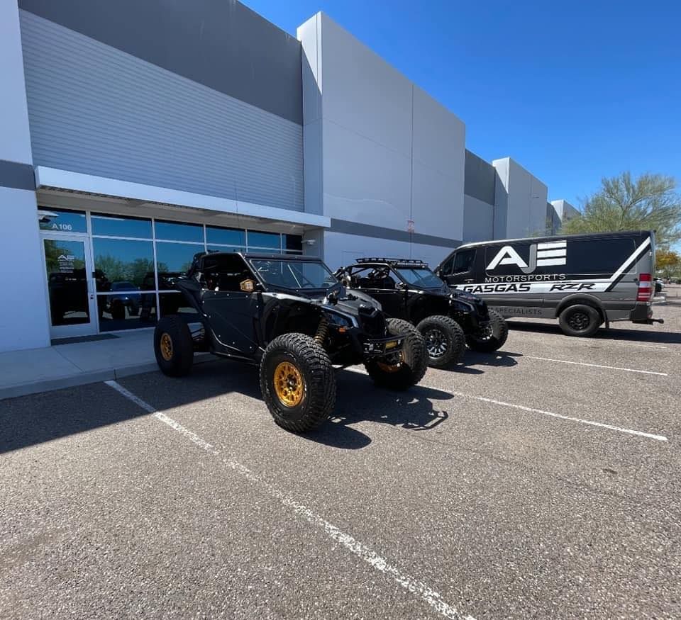 Several vehicles are parked in front of a building that says ae