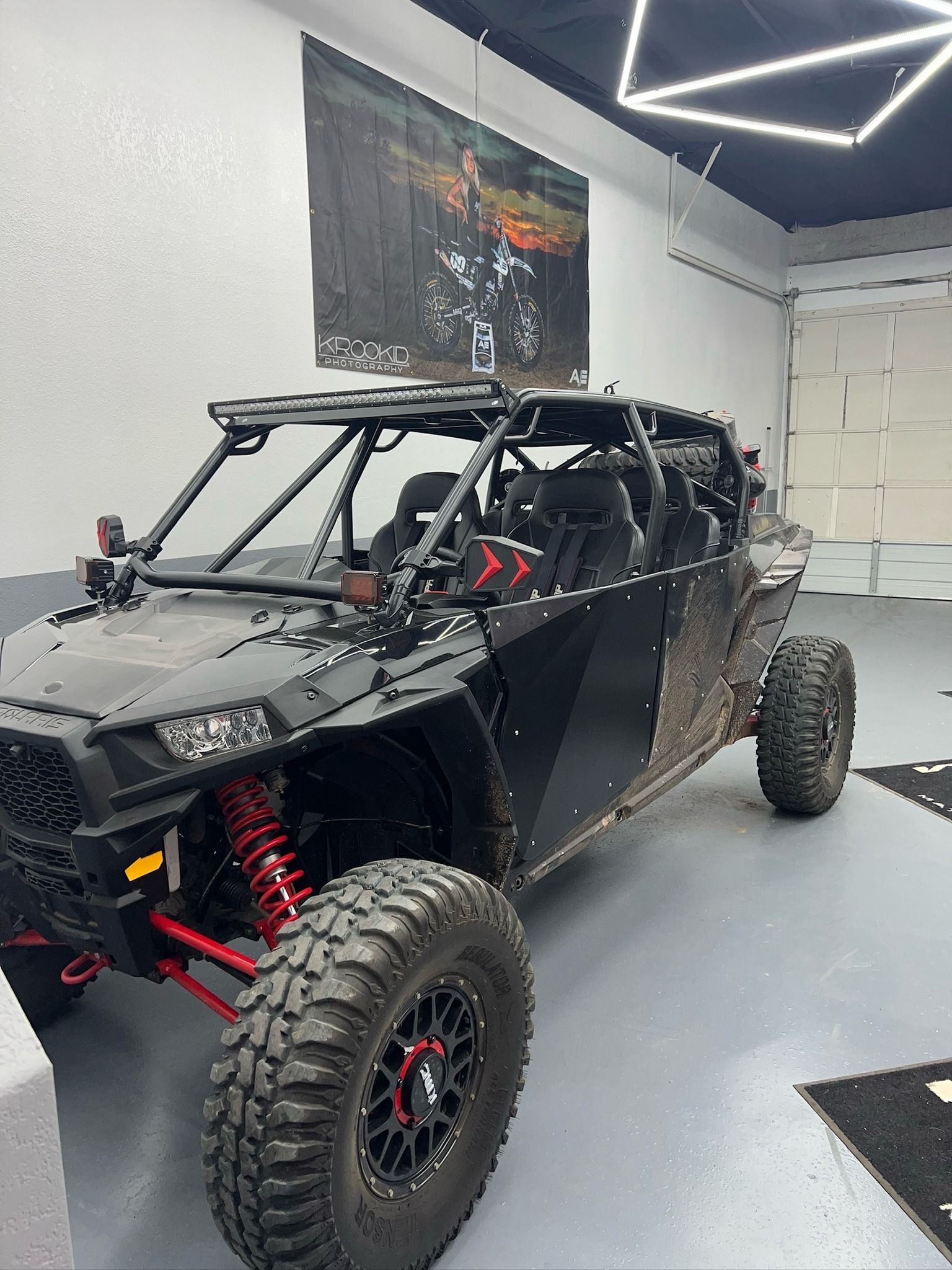 A black atv is parked in a garage next to a wall with a picture of a motorcycle on it.