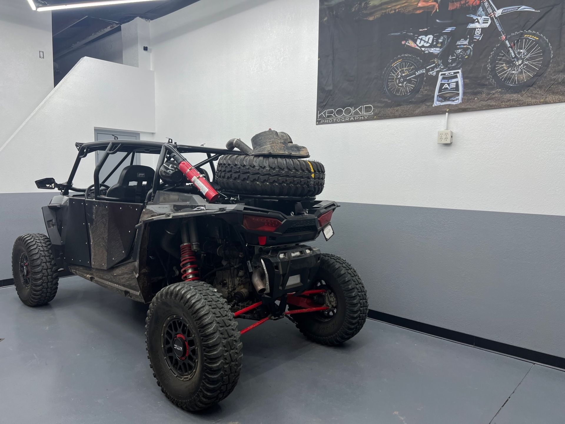 A atv is parked in a garage with a picture of a motorcycle on the wall.