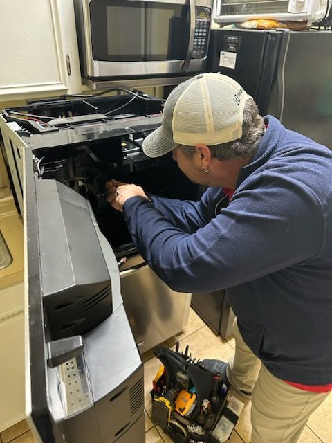 A man is working on a refrigerator in a kitchen.