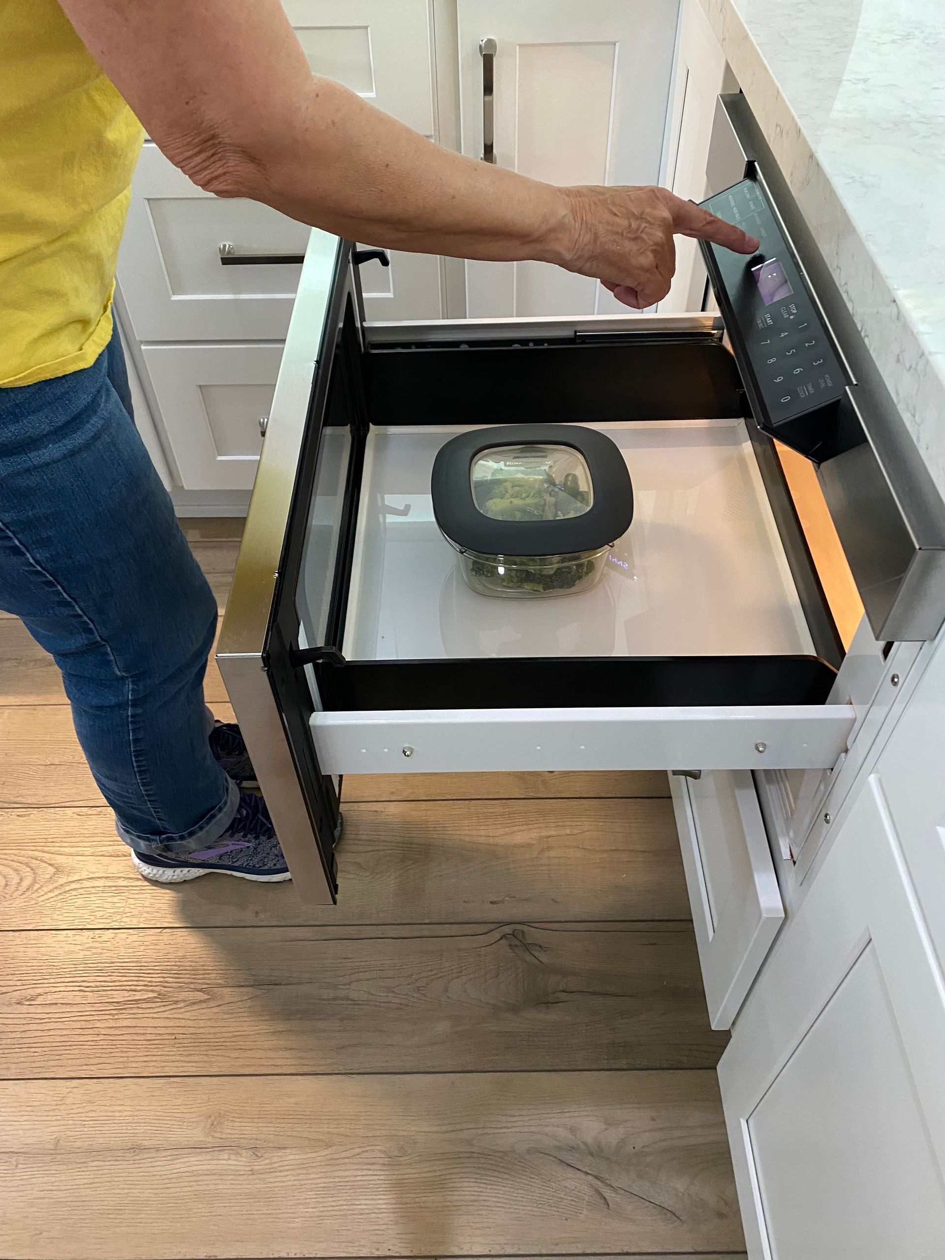 A woman is taking a bowl out of a microwave oven.