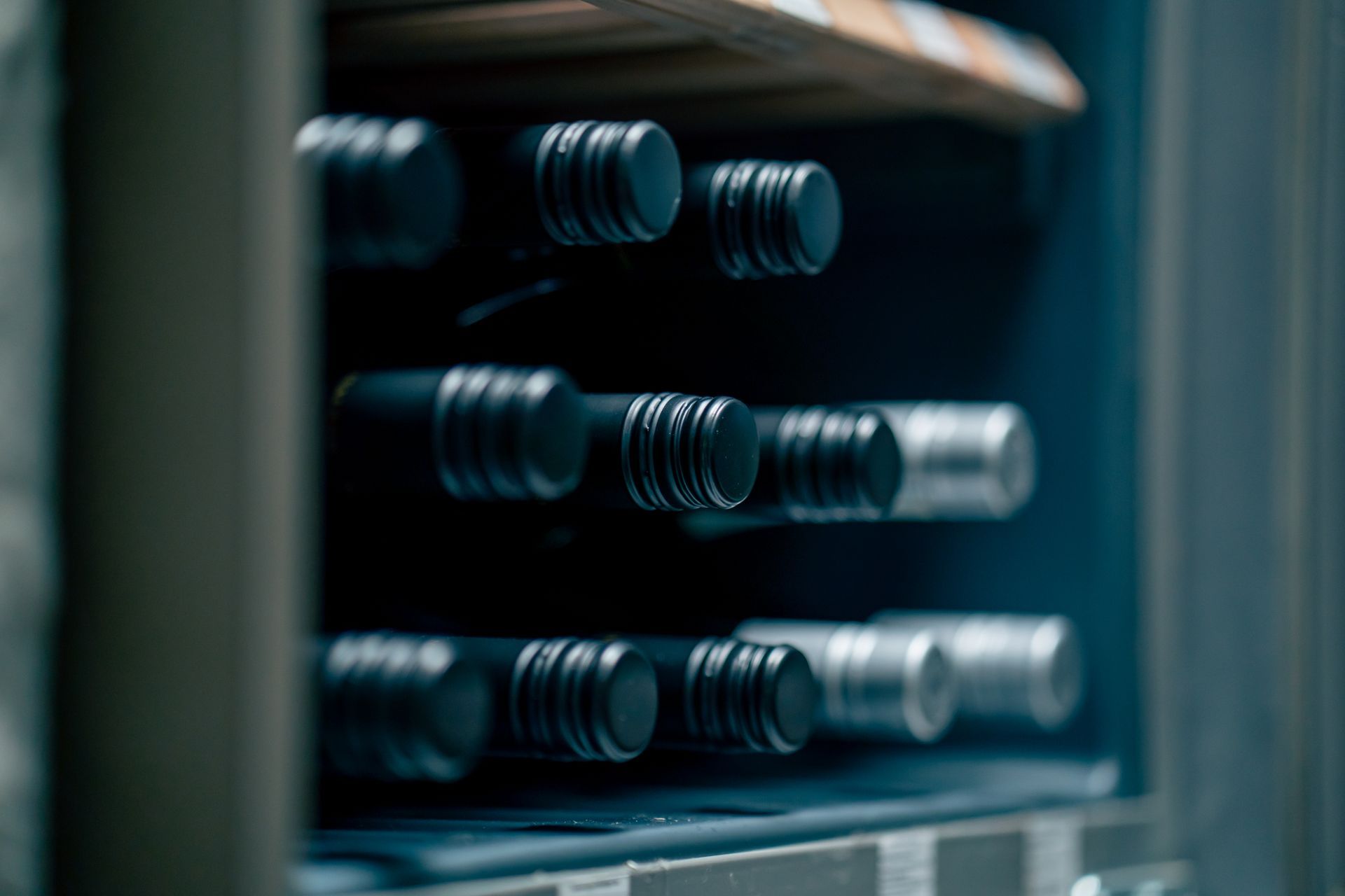 A row of wine bottles sitting on top of each other in a wine cooler.