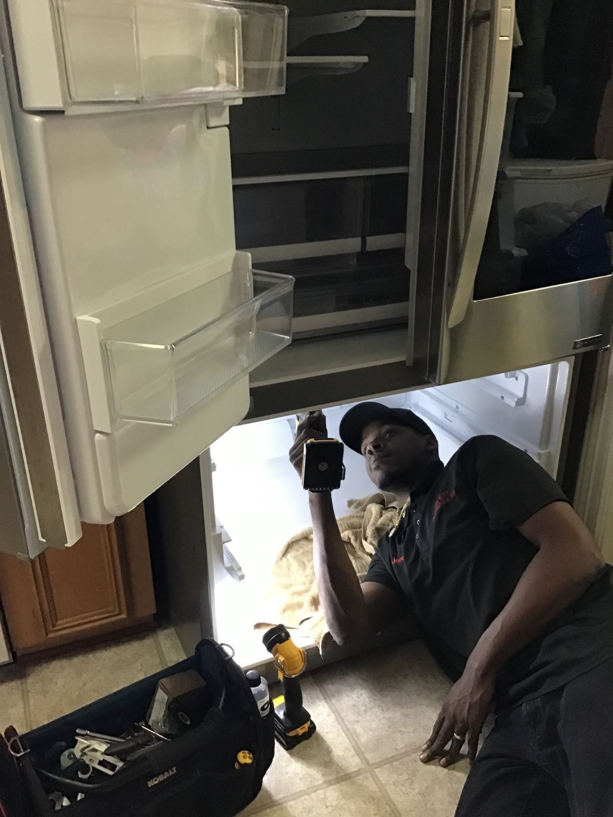 Appliance repair technician diagnosing a refrigerator in a Benton LA home