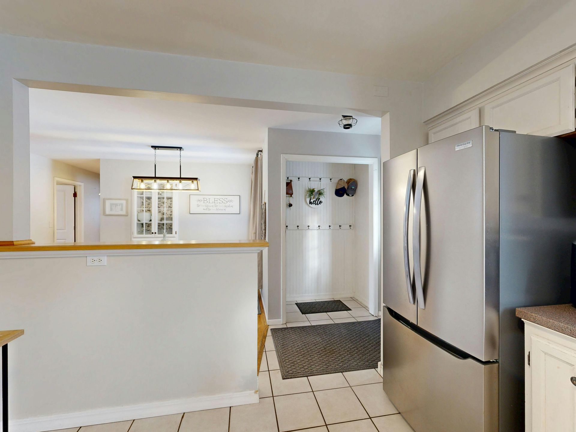 Modern stainless steel refrigerator in clean white kitchen with proper ventilation clearance