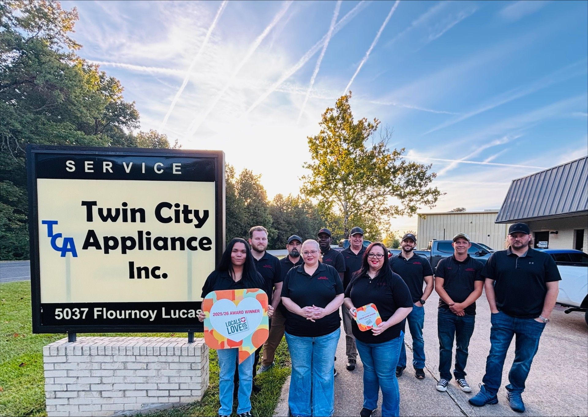 A group of people are posing for a picture in front of trucks.