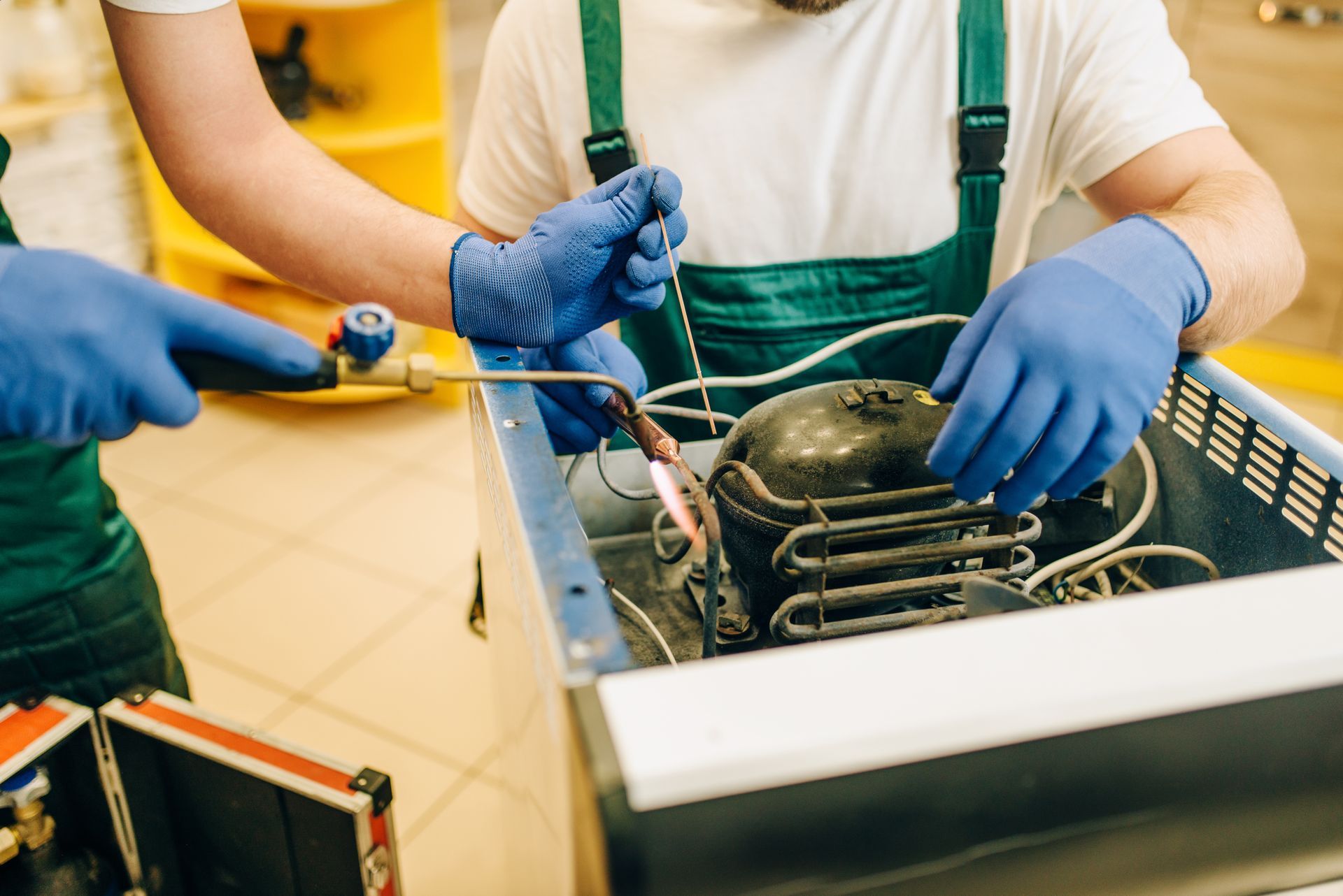 Two men are working on a refrigerator in a factory.