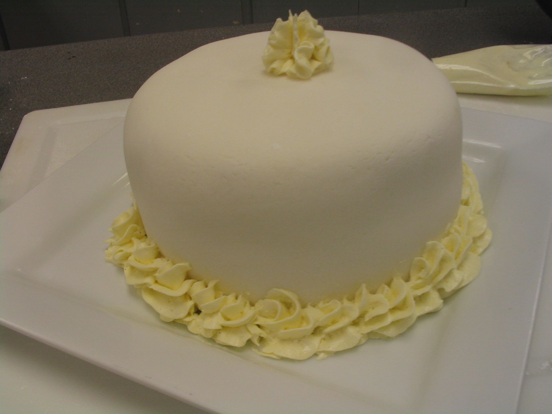 Yellow cake wrapped in Fondant and trimmed in Buttercream