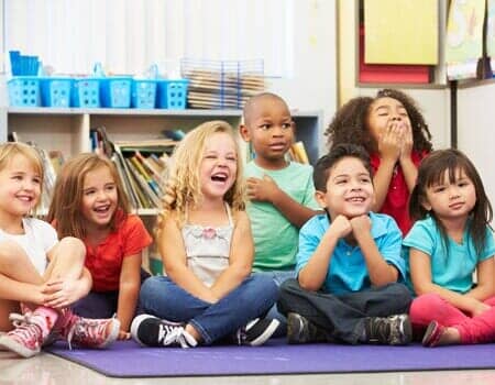 Happy Children in a elementary class sitting on a blue mat in Lombard, IL