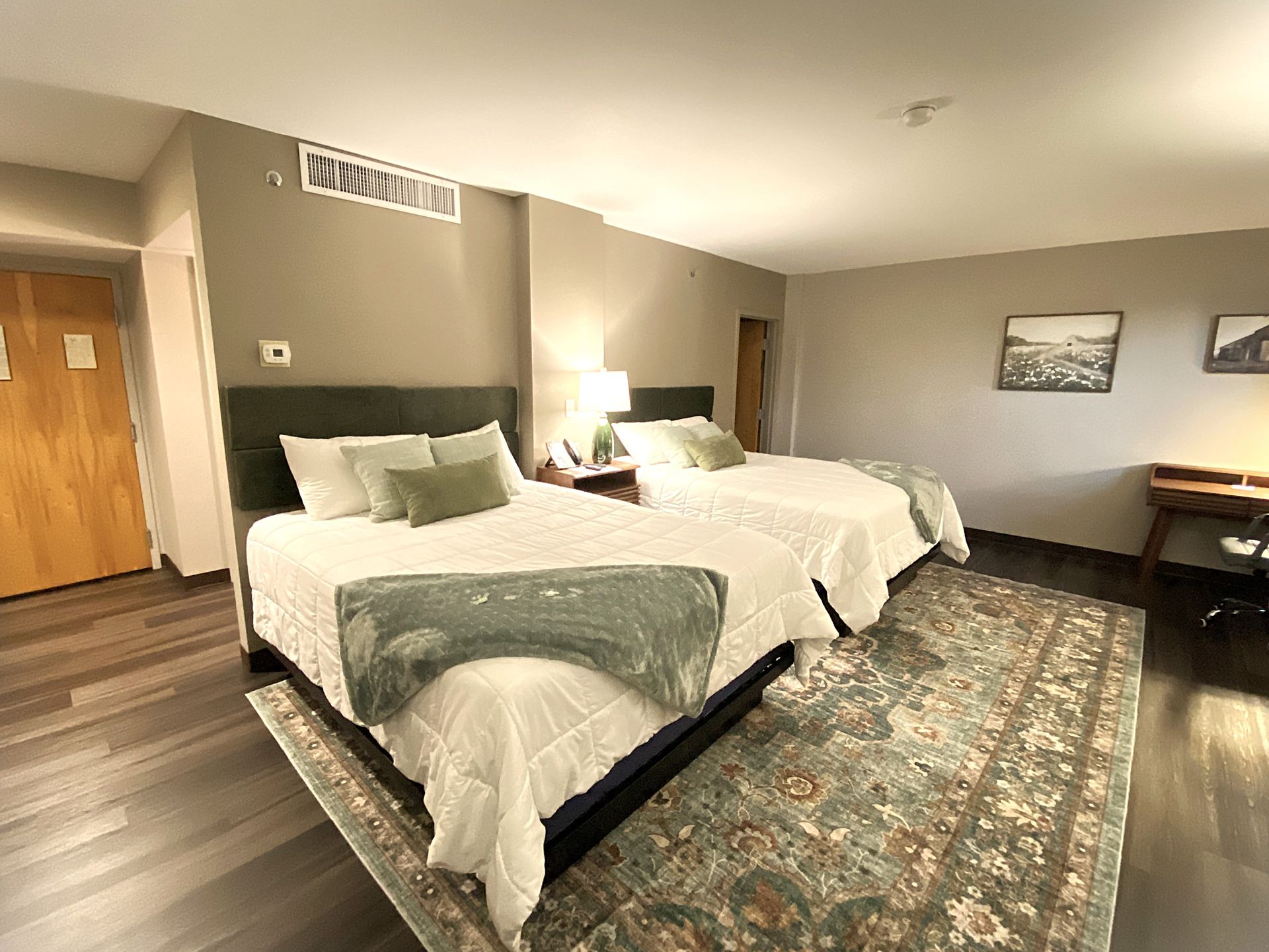 A hotel room with two beds and a rug.