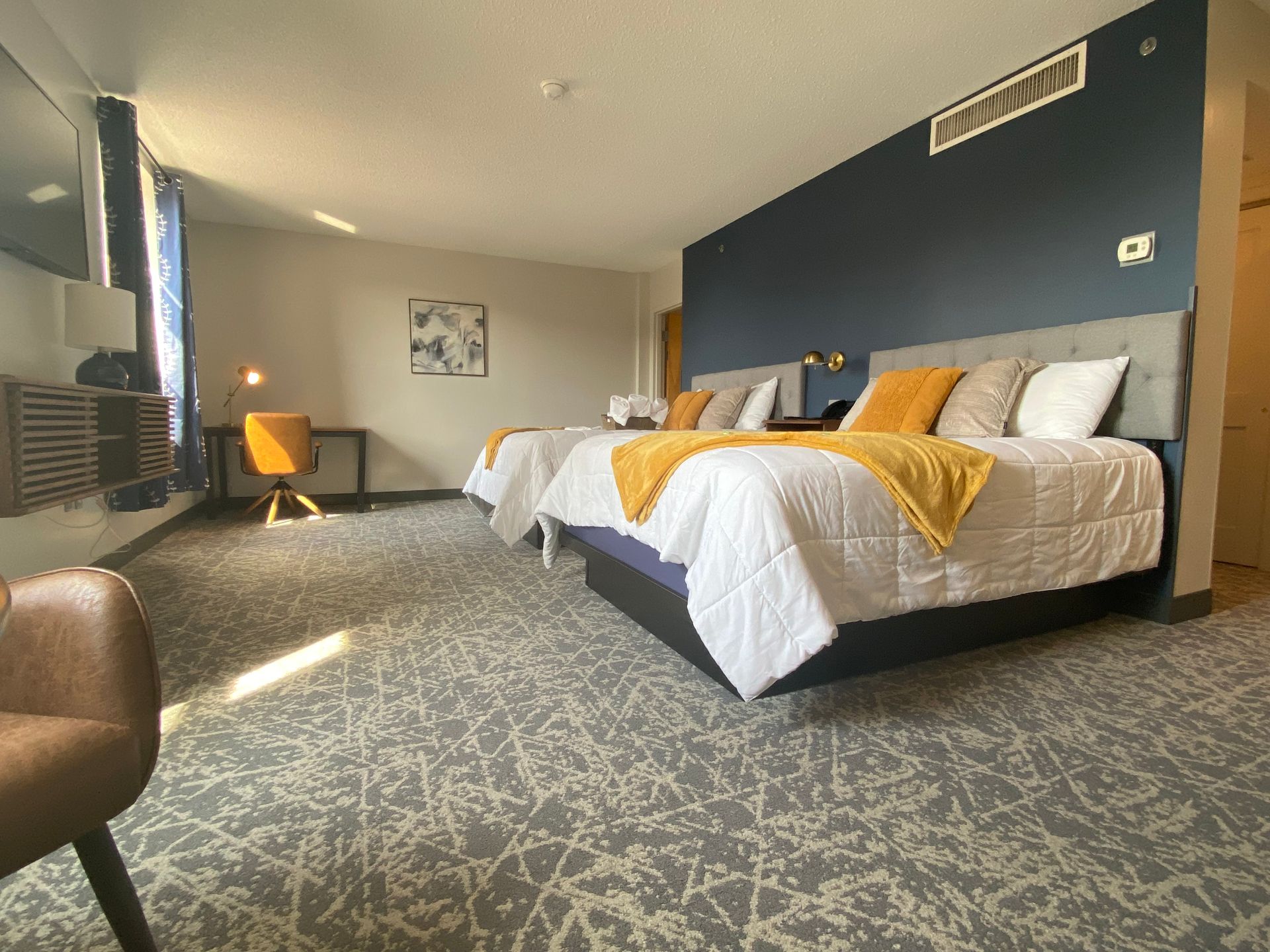 A hotel room with two beds , a desk and a chair.