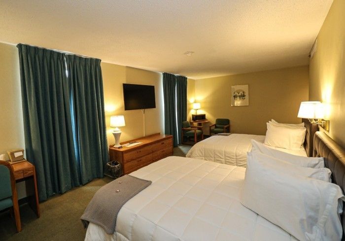 A hotel room with two beds , a desk and a television.