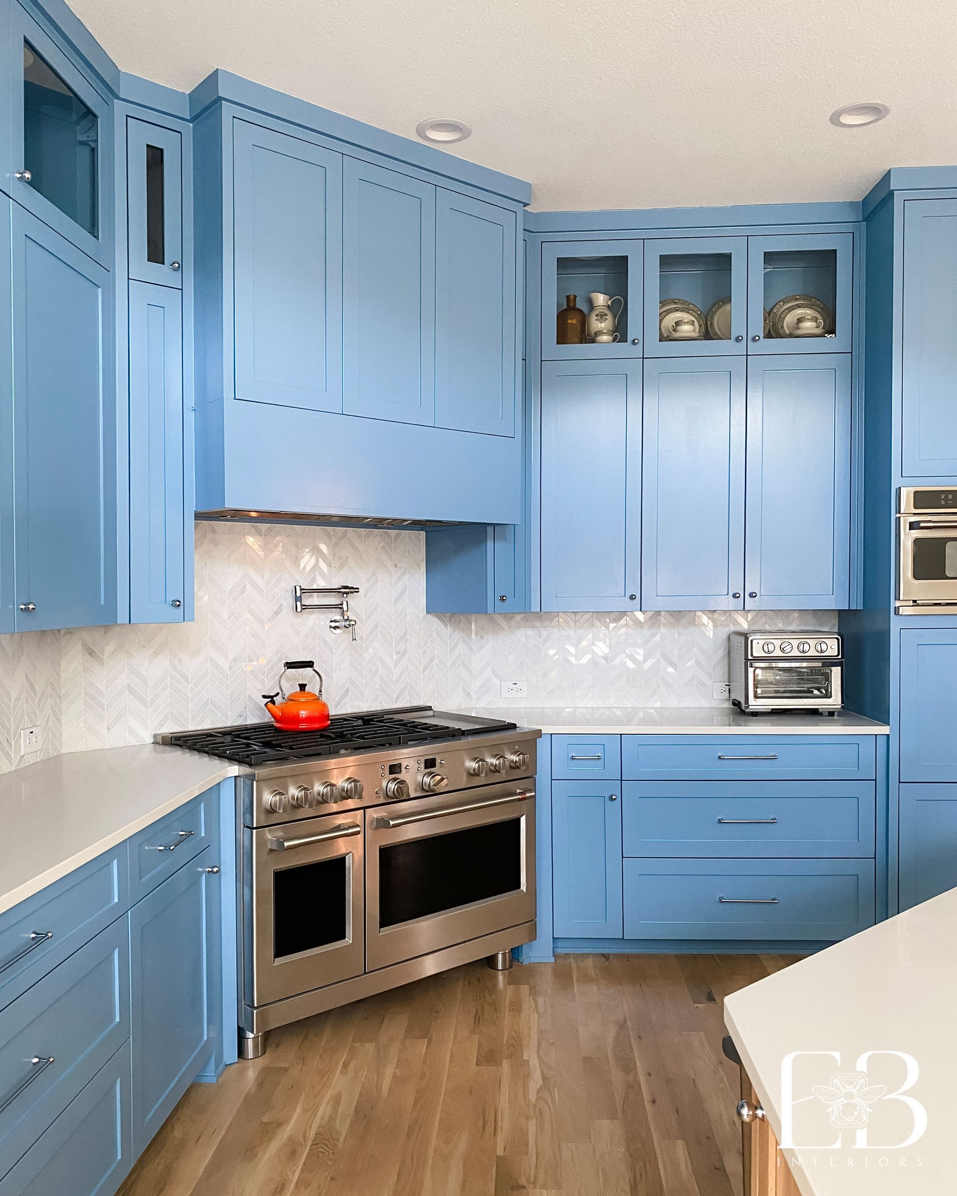 Kitchen with rattan bar stools, white cabinets, and gold pendant lights.