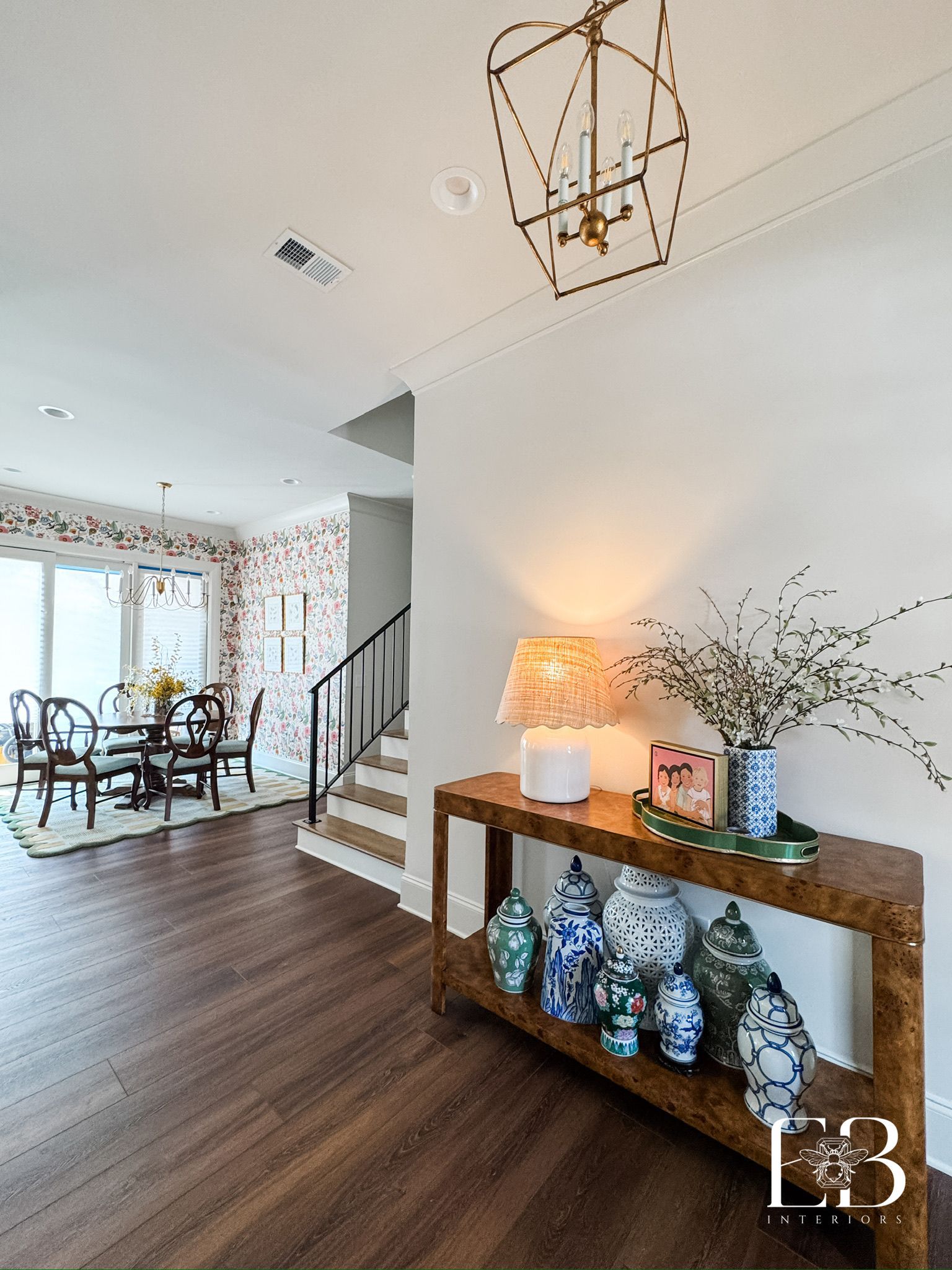 Entryway with a wooden table, decorative vases, lamp, dining room table, and staircase.