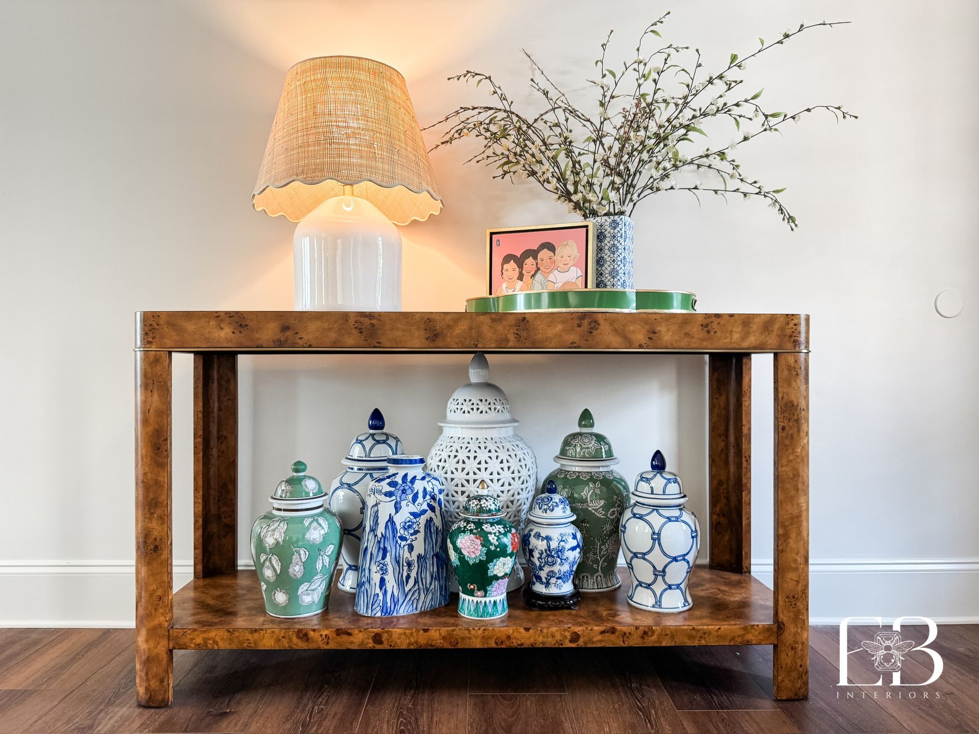 A wooden console table displays ginger jars and a lamp against a white wall.