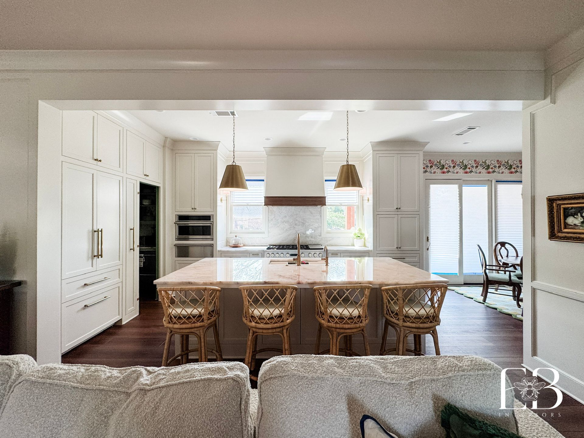 Kitchen with white cabinets, island with seating, and dark wood floors.