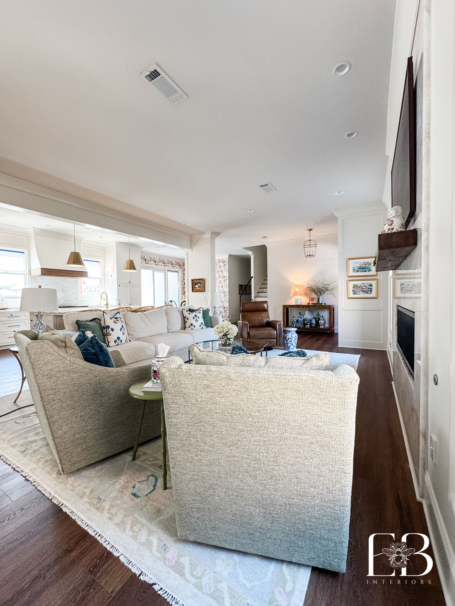 Spacious living room with light-colored furnishings, hardwood floors, and fireplace.