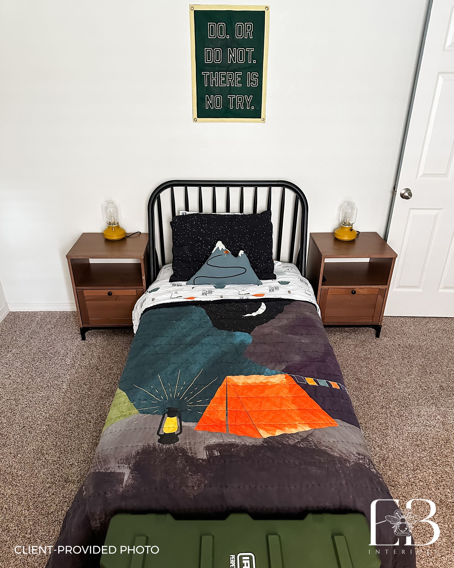 Bedroom with bed featuring a camping-themed quilt and pillow, wooden nightstands, and a sign.