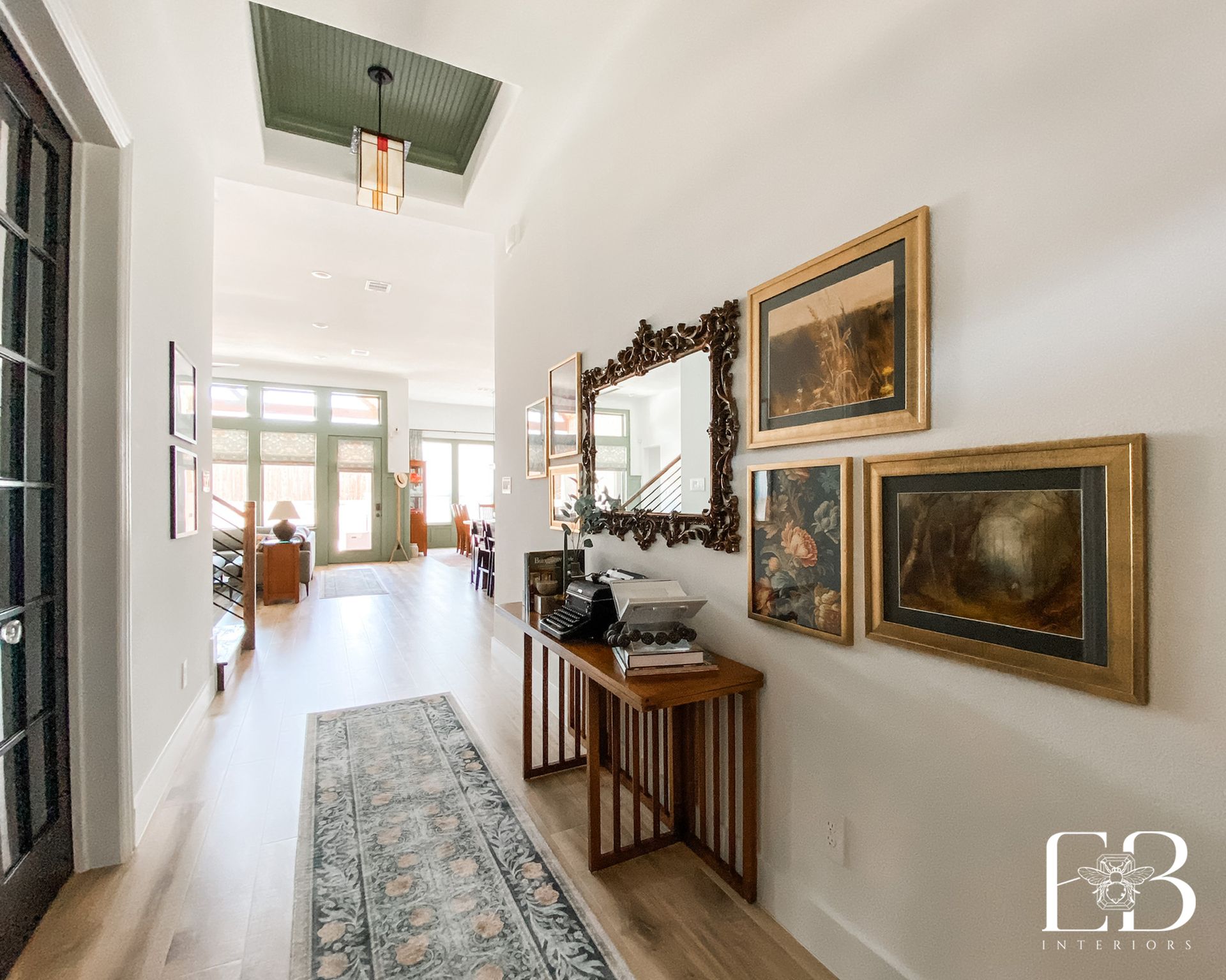 Hallway with art, a console table, and a green ceiling detail.