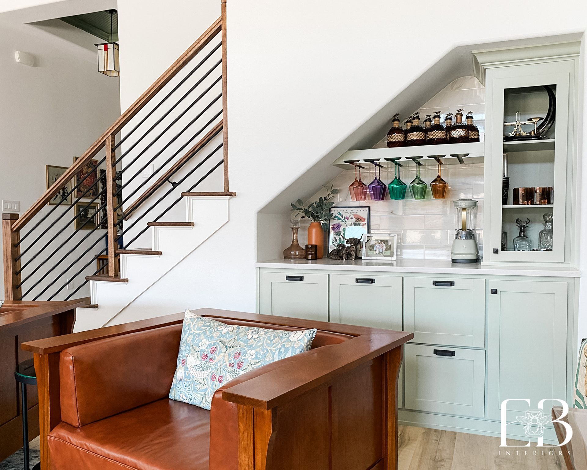 Bar area built into the space under stairs. Features a cabinet, wine rack, and a brown leather armchair.