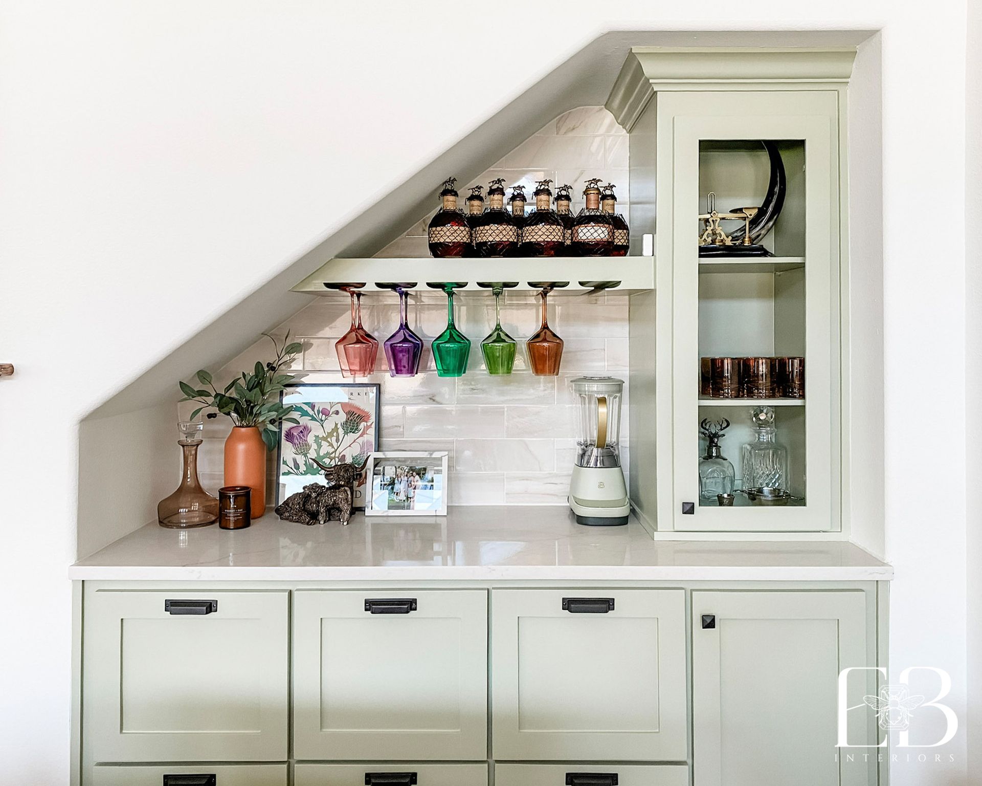 Built-in bar with light green cabinets, a quartz countertop, and glass shelves under a sloped ceiling.