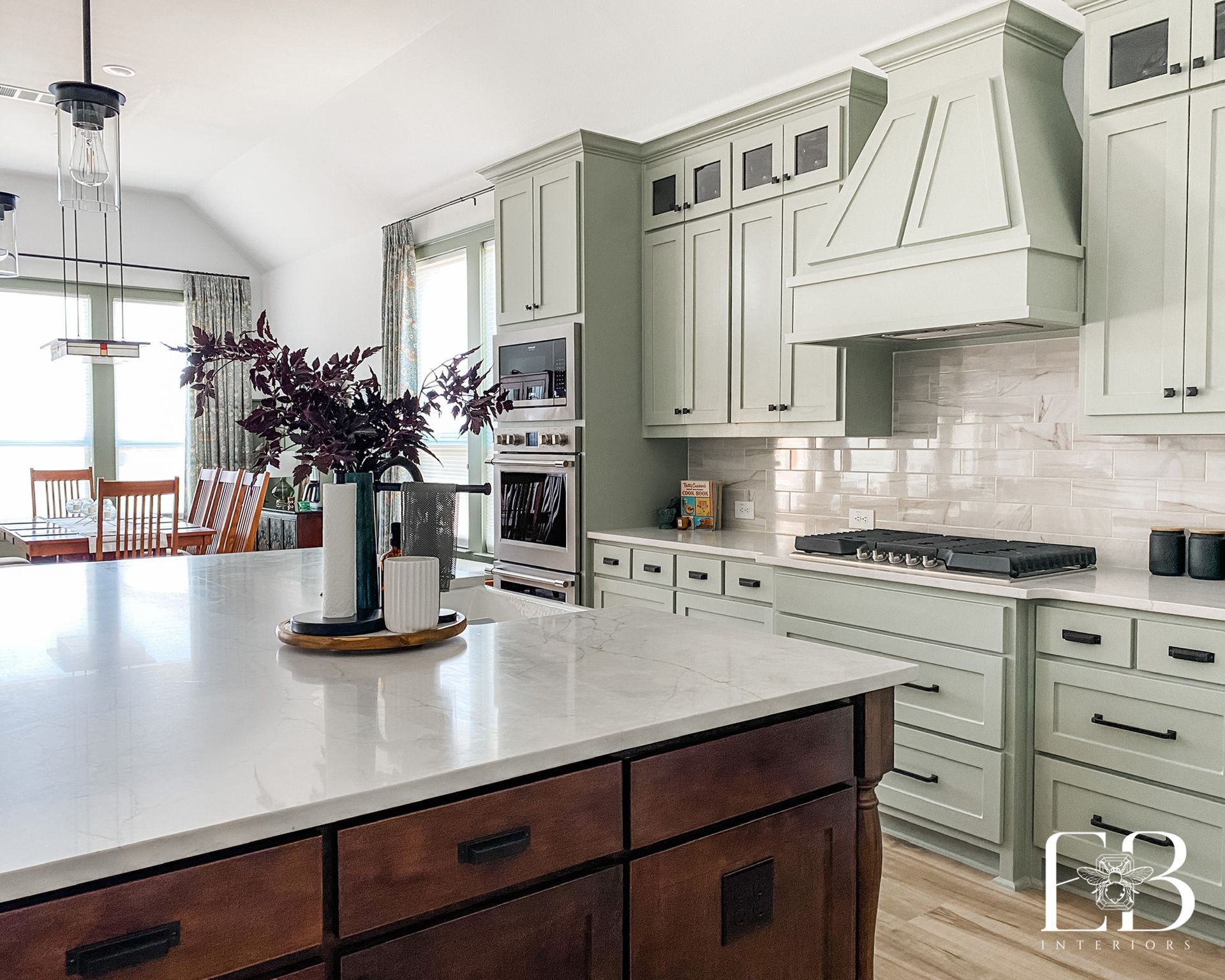 Kitchen with green cabinets, a dark wood island, and white countertops.