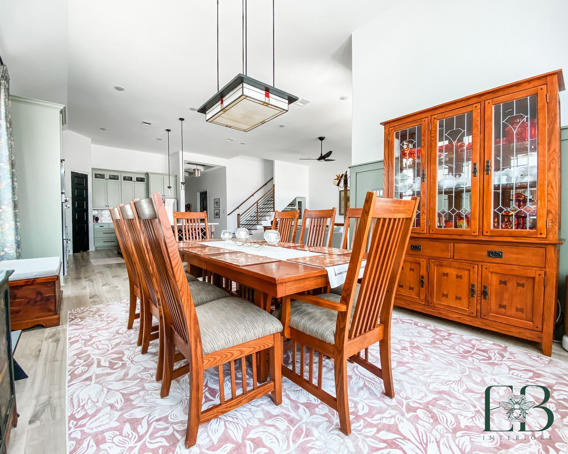Dining room with a wooden table, chairs, and hutch on a patterned rug.
