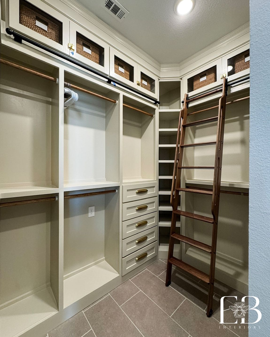 Custom walk-in closet by Emerald Bee Interiors with rolling ladder, brass-detailed drawers, and woven storage baskets.