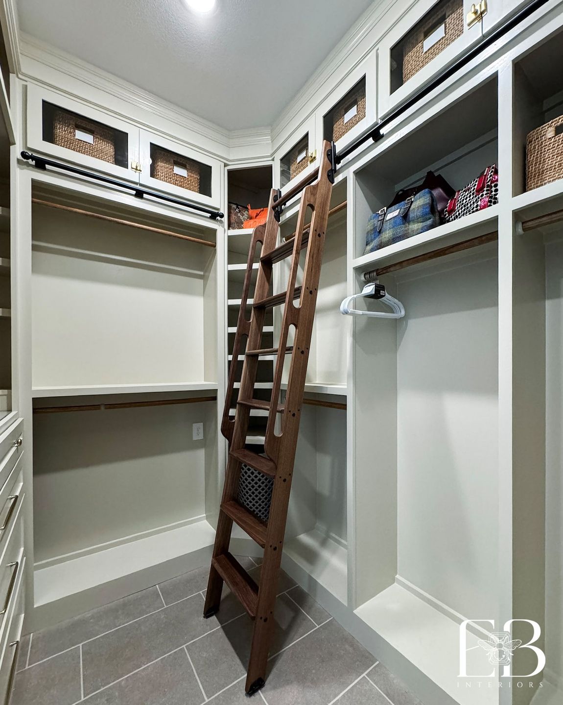 Closet with built-in cabinetry, upper baskets, and rolling ladder access by Emerald Bee Interiors for the Devotion Row home.