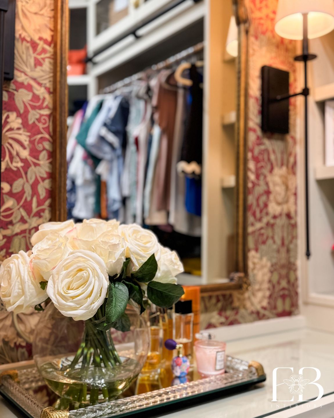 Vanity detail with roses and perfume bottles against red and gold wallpaper, styled by Emerald Bee Interiors.