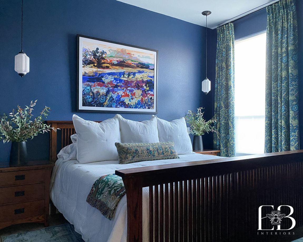 Navy blue guest bedroom by Emerald Bee Interiors with mission-style furniture, botanical drapery, and bold landscape artwork.