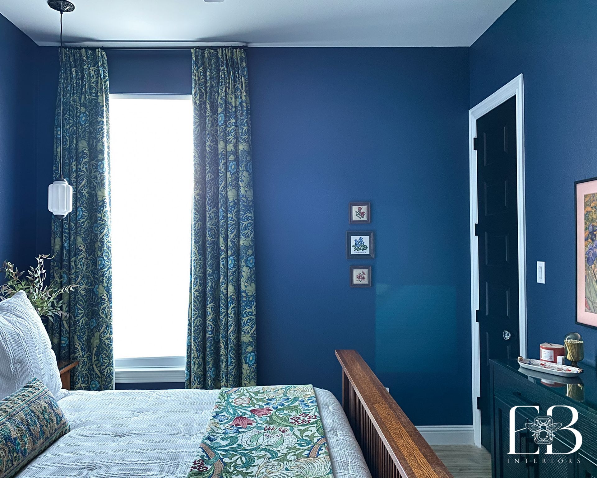 Bedroom with blue walls, patterned curtains, and a bed with a floral quilt.