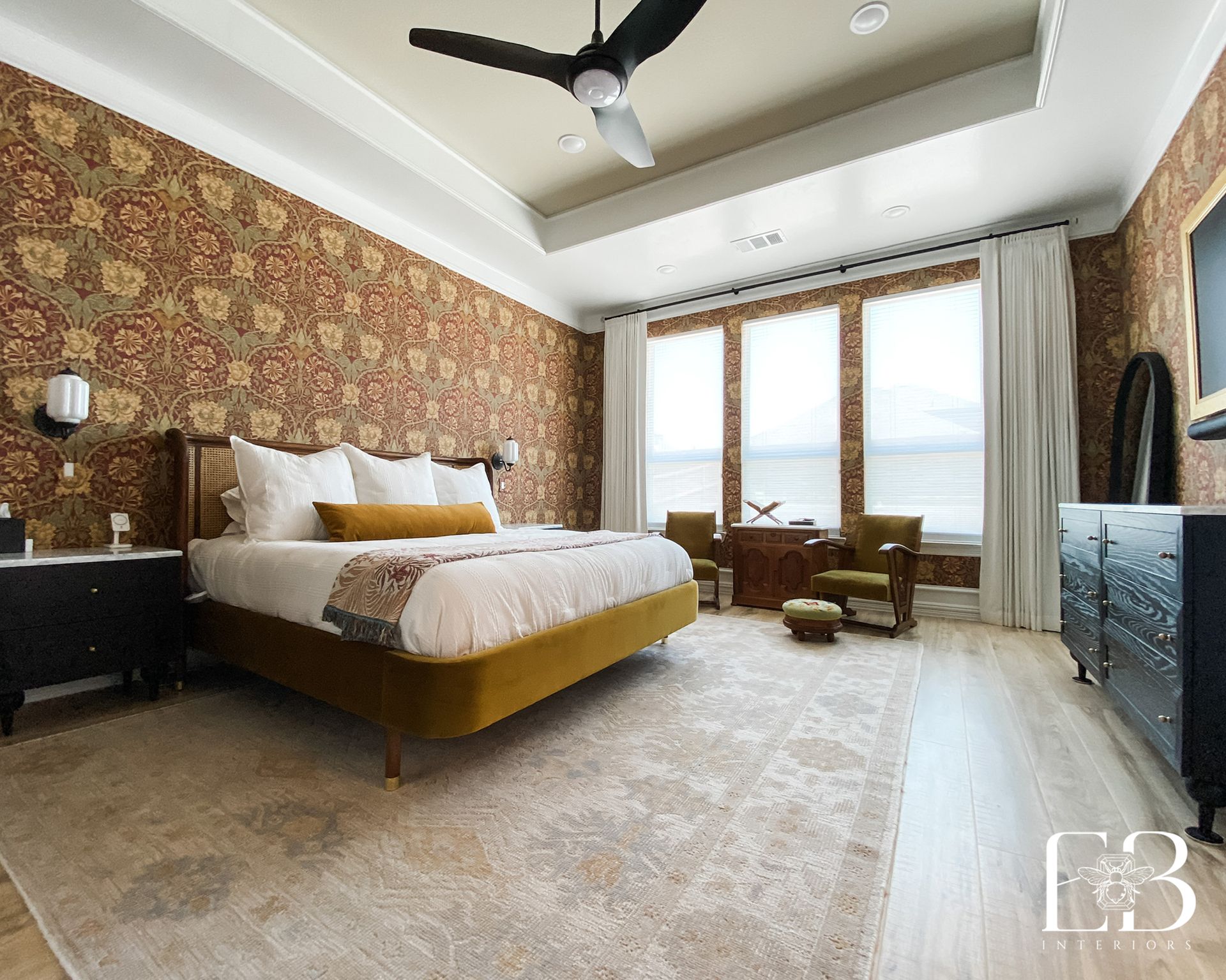 Bedroom with patterned wallpaper, gold bed, and black furniture.