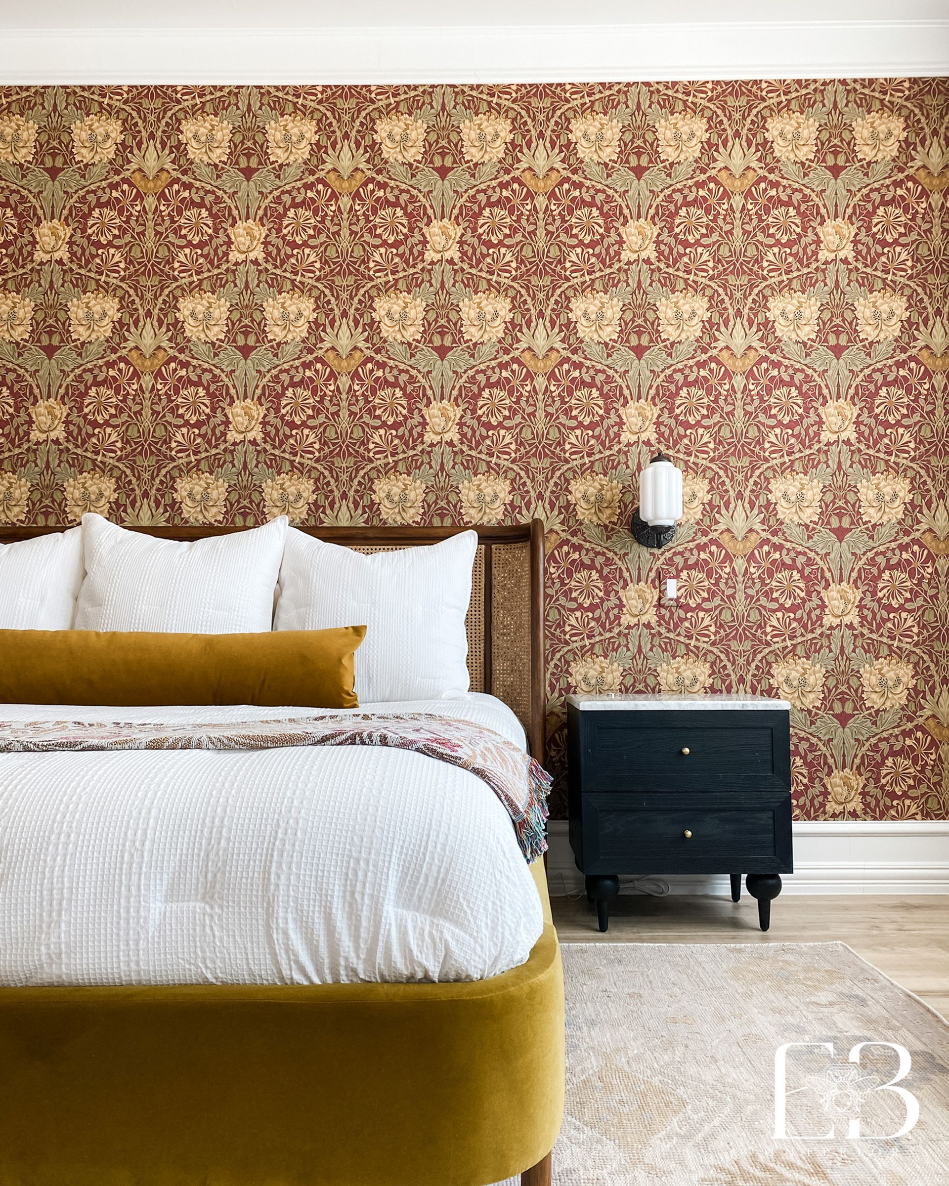Bedroom with patterned red wallpaper, a mustard yellow bed, and a black nightstand.