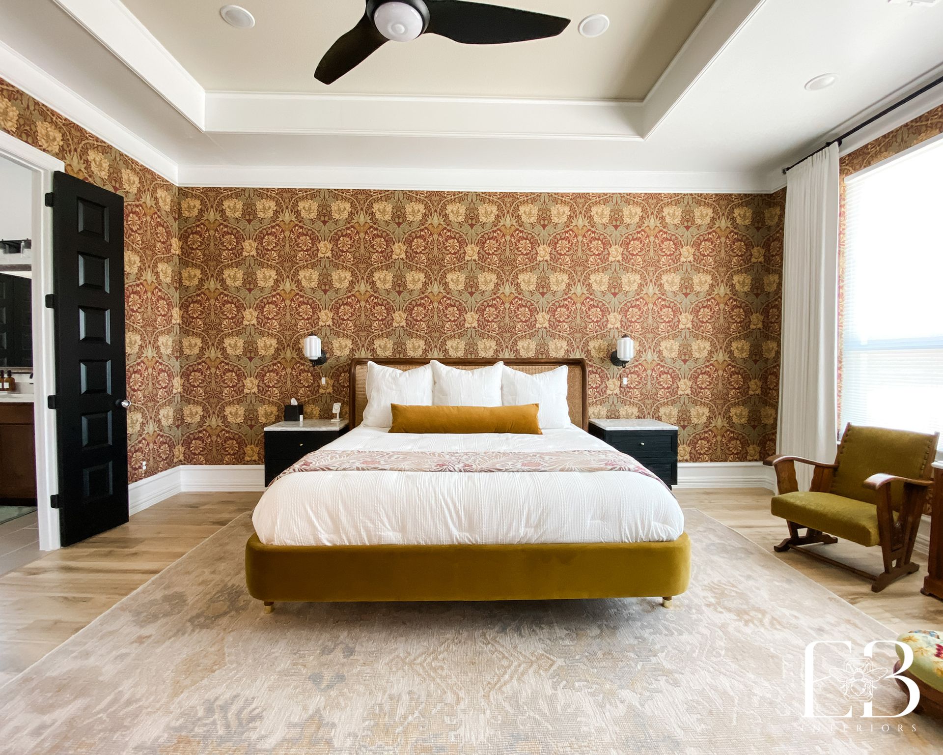 Bedroom with patterned wallpaper, mustard bed, black door, and a green chair.