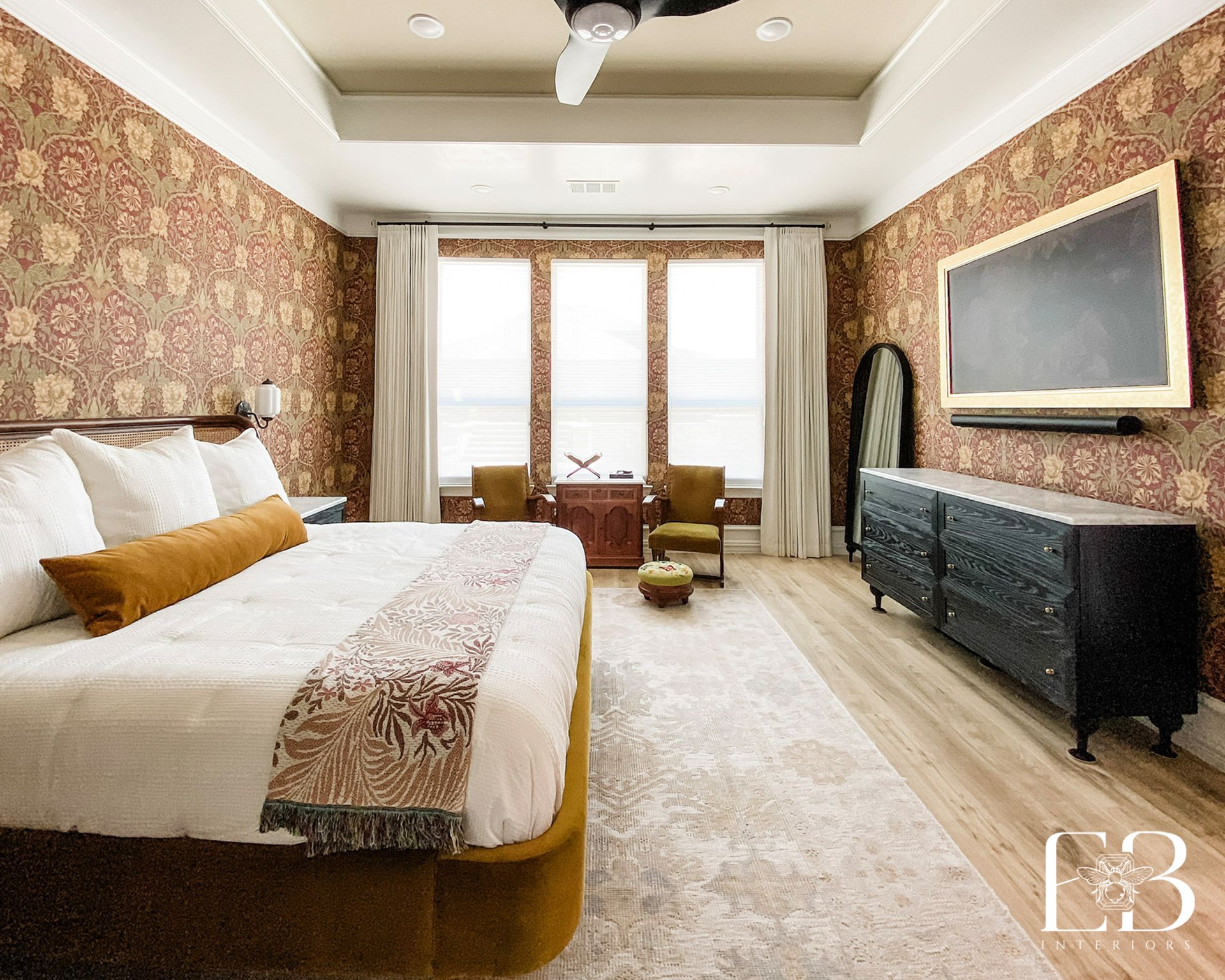 Bedroom with patterned wallpaper, large bed, TV, and light wood floors.