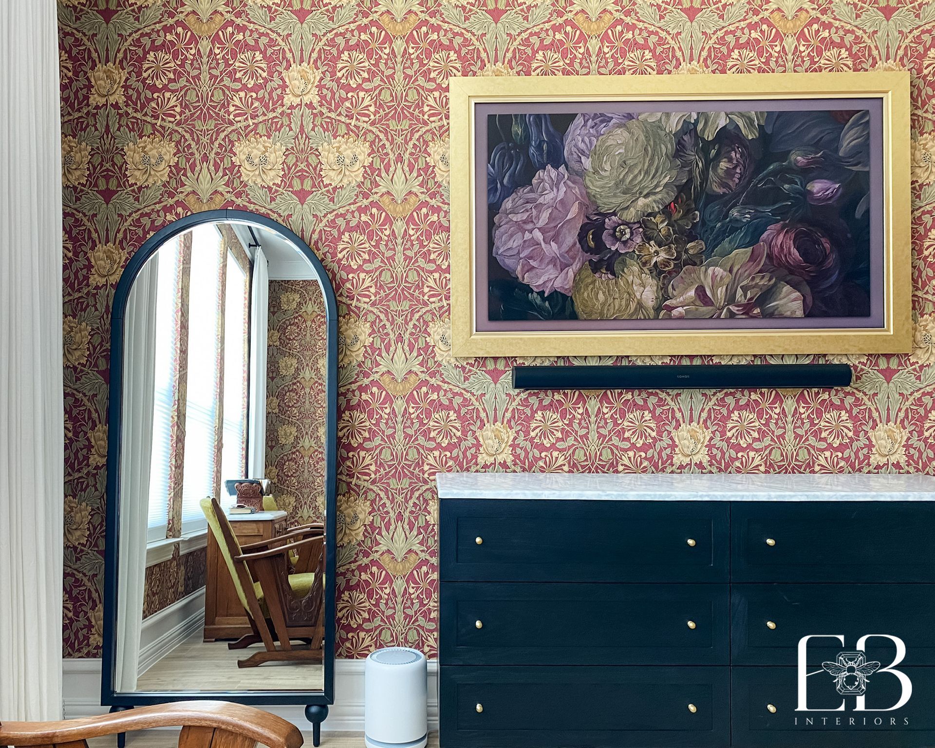 Room with floral wallpaper, mirror, dresser, art, and soundbar.