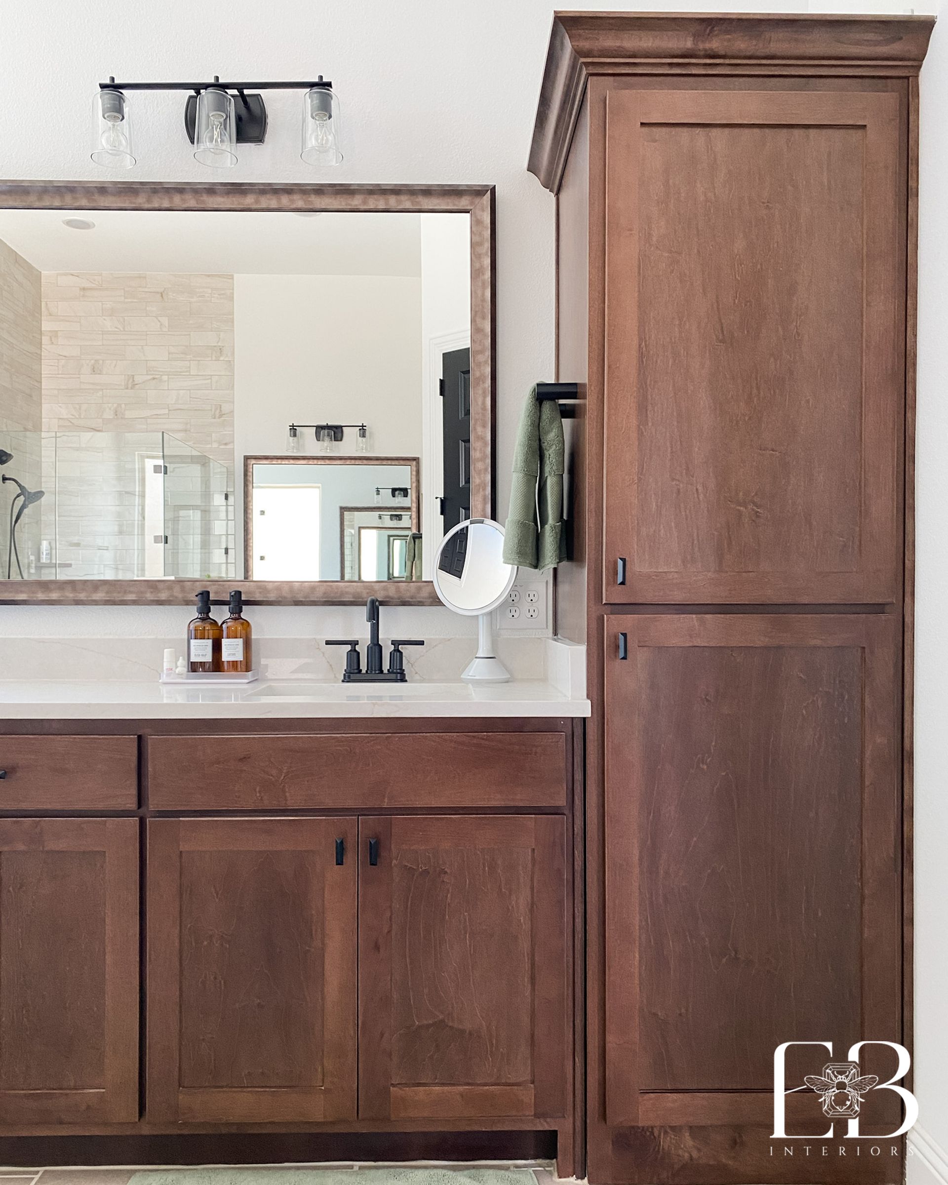 Bathroom with dark wood cabinets, white countertop, and large mirror.