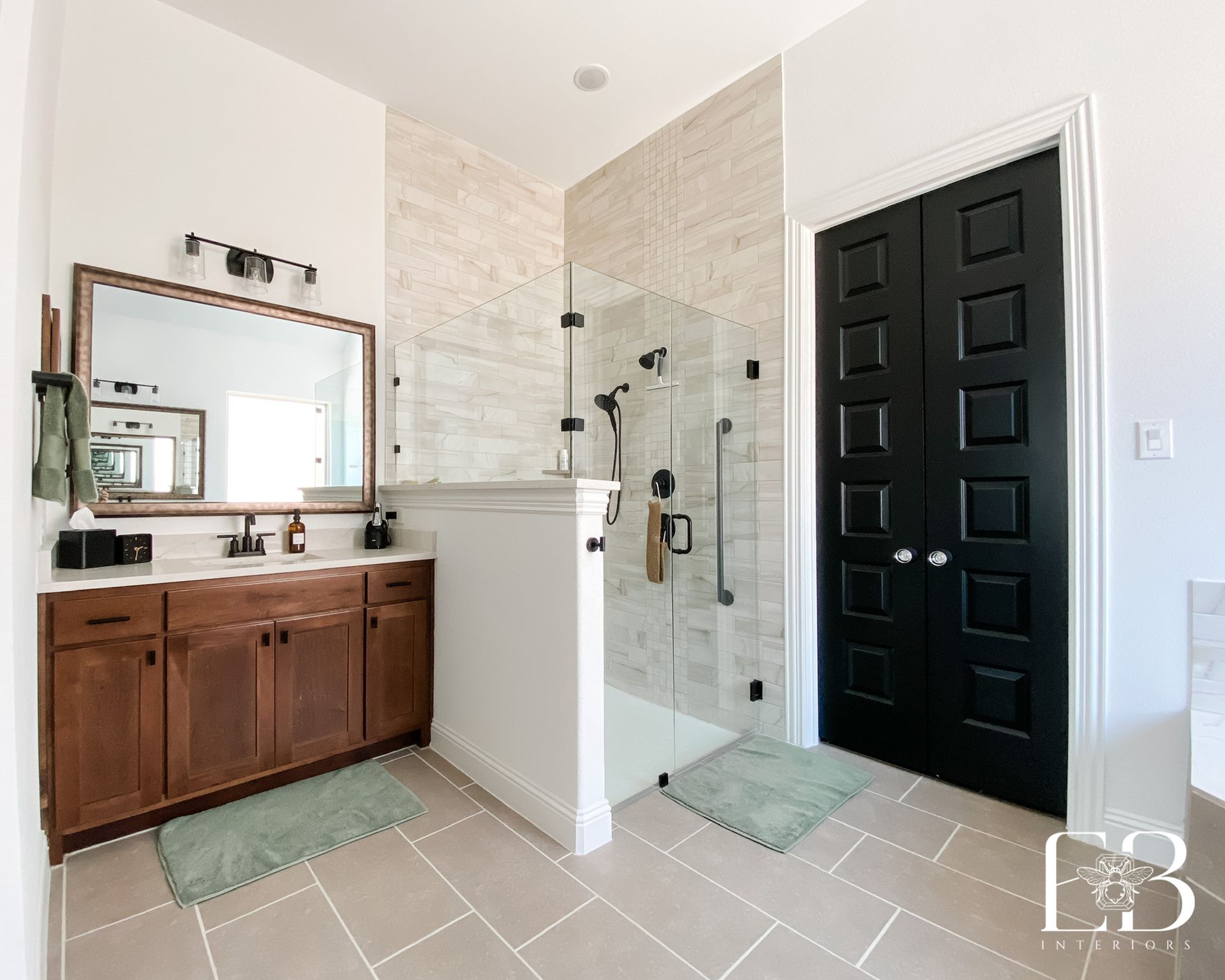 Bathroom with a brown vanity, black doors, and a glass shower.
